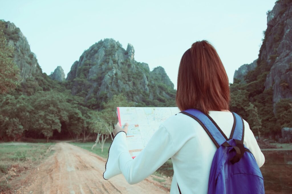 Young woman with a backpack explores nature using a map, surrounded by scenic mountains.